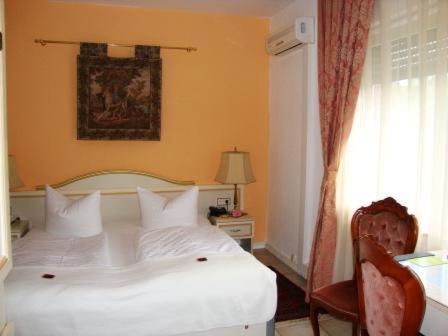 a bedroom with a white bed and a chair and a window at Haus Mooren, Hotel Garni in Düsseldorf
