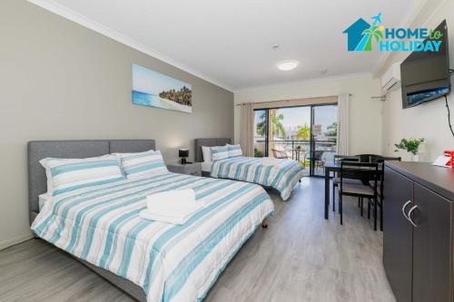 a bedroom with two beds and a kitchen with a desk at Marina View Studio - Steps away from CBD, Ferry & Stadium in Townsville