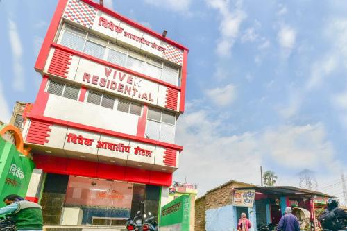 a red and white building with people standing in front of it at Hotel O Vivek in Hājīpur