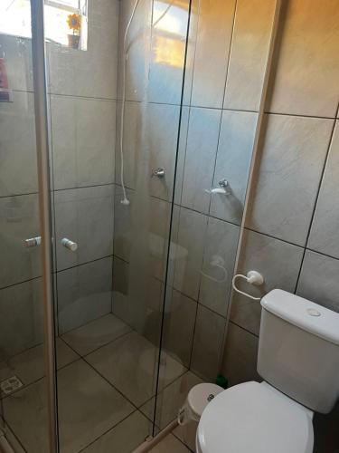 a bathroom with a glass shower with a toilet at Casa aconchegante inteira - Casa por Dia Imbituba SC in Imbituba