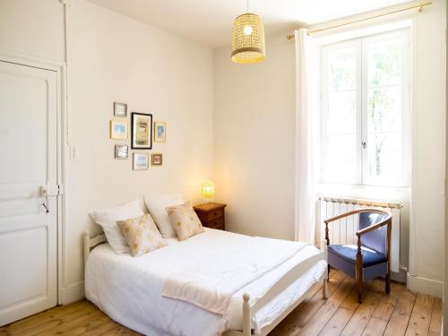 a bedroom with a white bed and a blue chair at Charming House in Coubjours with Pool in Coubjours