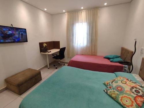 a hotel room with two beds and a desk at Meu aconchego com hidromassagem e churrasqueira in Sao Paulo