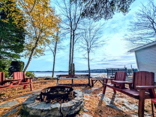 a fire pit with benches and a table and chairs at Back of the Moon Lakefront Camp family watersports fire pit 1 dog beach sleeps 8 in Sullivan