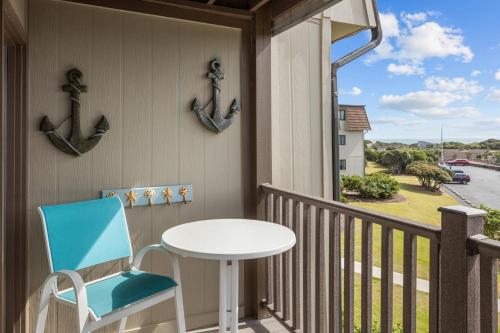 a table and a chair on a balcony with an ocean view at Summer School condo in Atlantic Beach