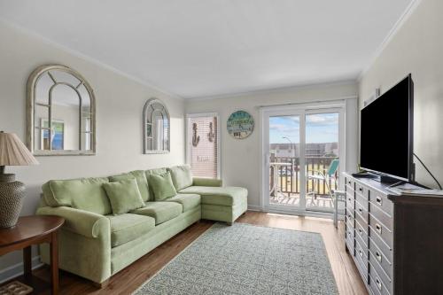 a living room with a green couch and a television at Summer School condo in Atlantic Beach