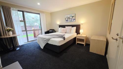 a bedroom with a bed and a large window at TOWER JUNCTION MOTOR LODGE- MOTEL with Airport and Railway Station Shuttle service- Best Location - close to Westfield Mall, Tower Junction Shopping Centre, Restaurants, Cafes etc in Christchurch