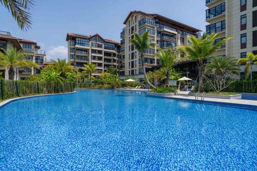 a large swimming pool with palm trees and buildings at Dreamscape Retreat Three-bedroom suite near Atlantis Hotel Sanya in Sanya