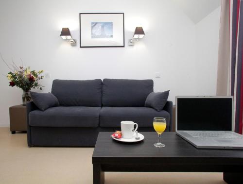 - un salon avec un canapé et une table avec un ordinateur portable dans l'établissement Odalys City Rennes Lorgeril, à Rennes