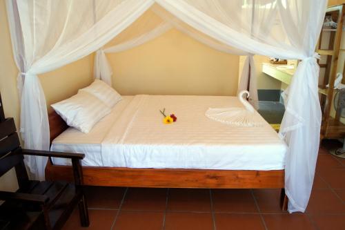 Una cama con un dosel blanco con una flor. en Gold Sand Beach Bungalow en Phu Quoc