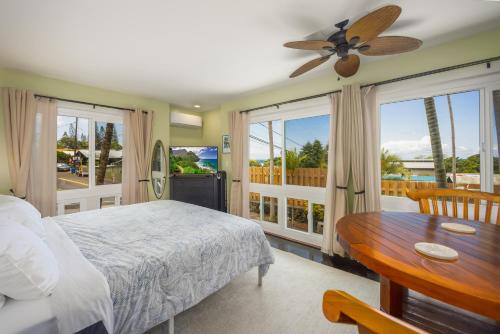 a bedroom with a bed and a table and windows at Kona Wave Rider - Island Sanctuary with Ocean Soul in Kailua-Kona