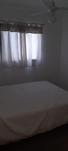 a bedroom with a white bed and a window at La Candelaria in La Punta