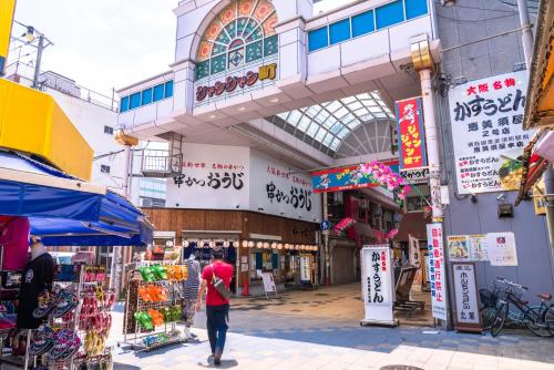 a man walking down a street in a market at the b osaka-shinsekai in Osaka