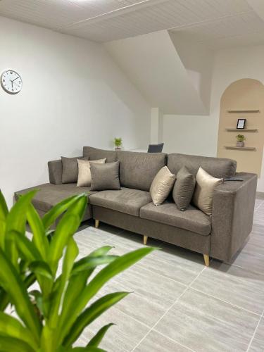 a couch in a living room with a clock on the wall at Apartamento Familiar con ubicación estratégica in Ibagué