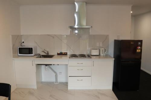 a kitchen with white cabinets and a black refrigerator at Nova Motel in Auckland