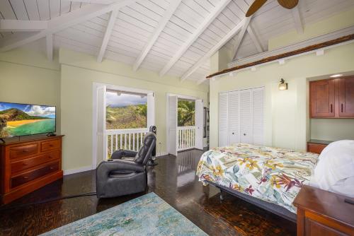 a bedroom with a bed and a tv and a chair at Kona Penthouse 2 Bedroom, Relax and Unwind Aloha Style in Kailua-Kona
