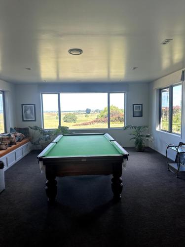 a pool table in a room with a large window at Homewood in Matamata