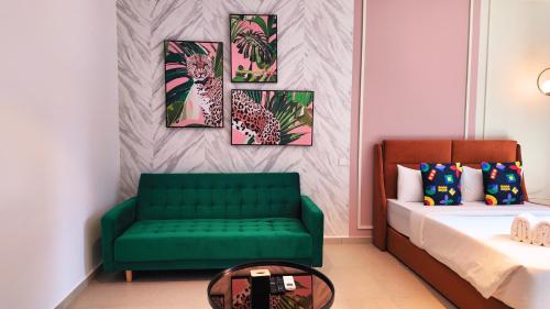 a bedroom with a green couch and paintings on the wall at Paxtonz Suite Kuala Lumpur in Petaling Jaya