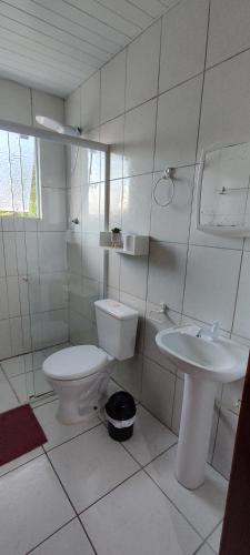 a white bathroom with a toilet and a sink at Descanse na Praia de Fora in Palhoça