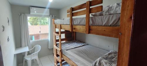 a bedroom with two bunk beds and a window at Descanse na Praia de Fora in Palhoça
