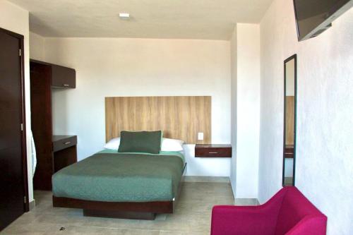 a hotel room with a bed and a red chair at Hotel Estrella Apt B in Zacatlán