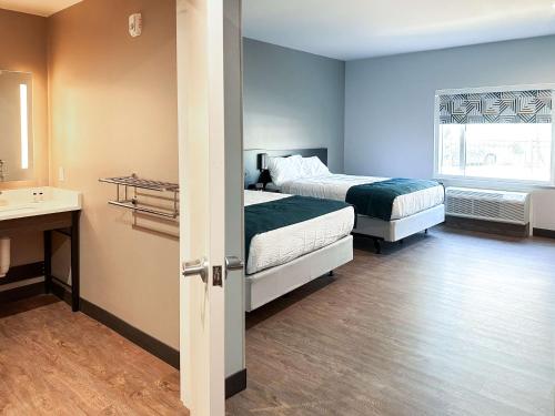 a bedroom with two beds and a sink and a window at Studio 6 Richmond-Airport in Sandston