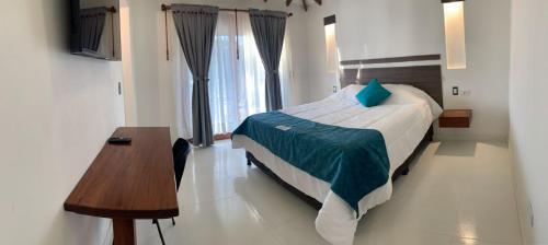 a bedroom with a bed and a desk and a table at hotel torres del viento in Villa de Leyva