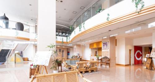 a lobby with tables and chairs in a building at Hotel SEASONS NICHINAN in Nichinan