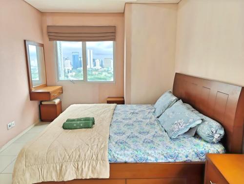 a bedroom with a bed with a green suitcase on it at Strategic 2BR Thamrin Apt with Pool & Gym by 2ndHome in Jakarta