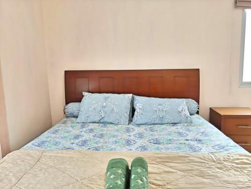 a bed with blue pillows and green shoes on it at Strategic 2BR Thamrin Apt with Pool & Gym by 2ndHome in Jakarta