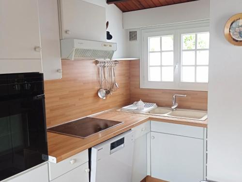 une cuisine avec des armoires blanches et un évier dans l'établissement Maison proche plage, 3 pers, animaux admis - FR-1-823-128, à Noirmoutier-en-l'lle
