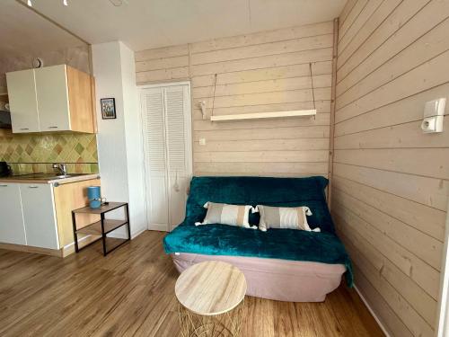 Cette petite chambre dispose d'un canapé bleu et d'une table. dans l'établissement Appartement au bord de la mer avec parking à Saint-Hilaire-de-Riez - FR-1-652-55, à Saint-Hilaire-de-Riez