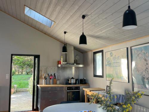 une cuisine avec des suspensions noires et une table dans l'établissement Villa contemporaine spacieuse proche de Sauzon avec jardin - FR-1-418-265, à Sauzon