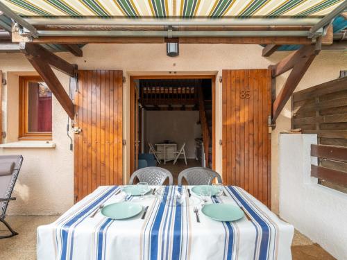 une table avec un tissu de table rayé sur une terrasse dans l'établissement Appartement duplex à deux pas de l'océan pour 4 personnes, cour privée, ménage inclus - FR-1-319-600, à Biscarrosse