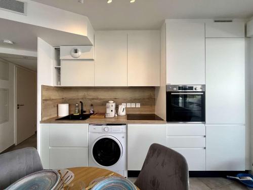 une cuisine avec des armoires blanches et une laveuse et une sécheuse dans l'établissement Bel appartement neuf 4 pers. avec terrasse, Cap d'Agde - FR-1-249-429, au Cap d'Agde