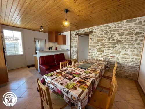 une salle à manger avec une table et un mur en pierre dans l'établissement Gîte familial à Talmont-Saint-Hilaire avec cour privée - FR-1-426-579, à Saint-Hilaire-de-Talmont