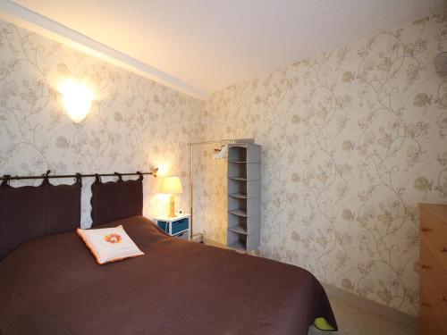 une chambre avec un grand lit avec une couverture marron dans l'établissement Mont-Dore T2 avec balcon et parking proche centre - FR-1-415-158, à Mont-Dore