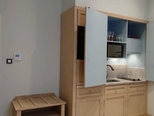 - une cuisine avec des placards en bois, un évier et un comptoir dans l'établissement Studio de charme climatisé centre de Pézenas, animaux admis - FR-1-607-212, à Pézenas