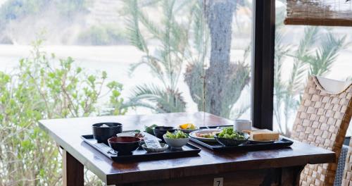 a table with plates of food on it with a window at Hotel SEASONS NICHINAN in Nichinan