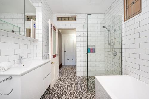 a white bathroom with a sink and a shower at Saint Francis in Fitzroy in Melbourne