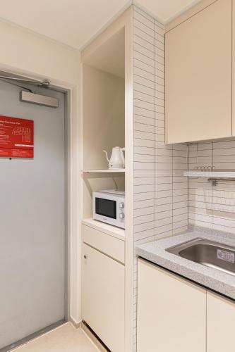 a kitchen with white cabinets and a microwave at Hotel Modak Namdaemun in Seoul