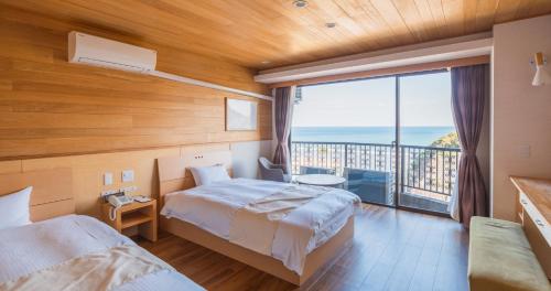 a bedroom with two beds and a large window at Hotel SEASONS NICHINAN in Nichinan