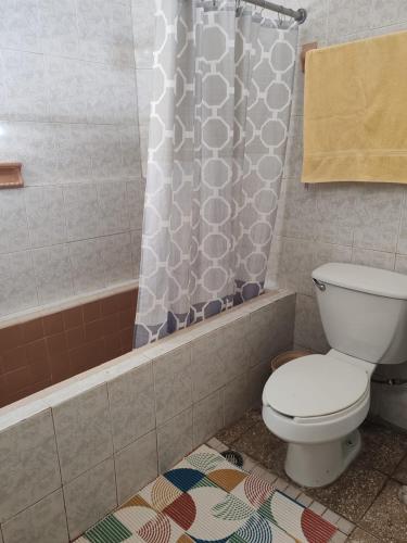 Un baño con inodoro y cortina de ducha. en Casa Kika, en Mazatlán
