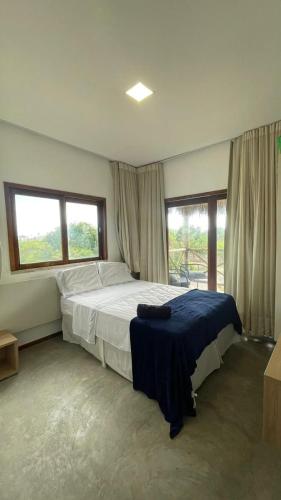 a bedroom with a large bed and two windows at Chale Praia Barrinha in Barrinha