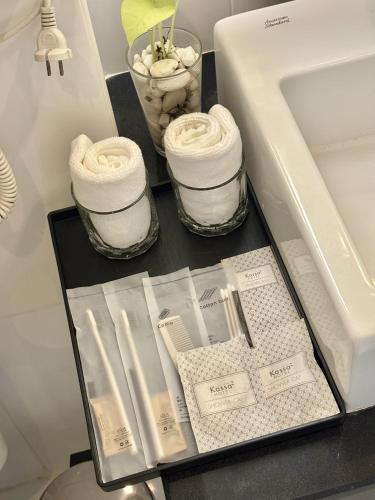 a counter with three jars of towels and a sink at Klassique Sukhumvit Hotel in Bangkok