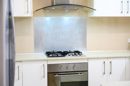 a stove top oven in a kitchen with white cabinets at 5BR Peaceful Oasis with Wifi Garage in Hornsby