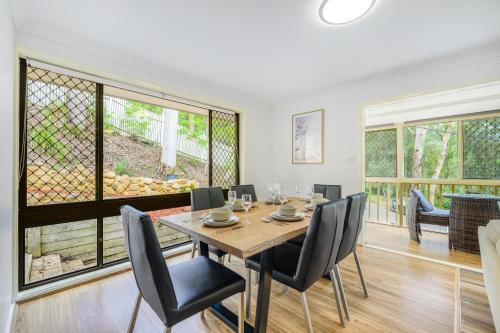 a dining room with a table and chairs and windows at 5BR Peaceful Oasis with Wifi Garage in Hornsby