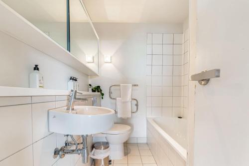 a white bathroom with a sink and a toilet at Luxury 2BR Apt Pool, Gym, Prime Spot Zodiak Stays in Auckland