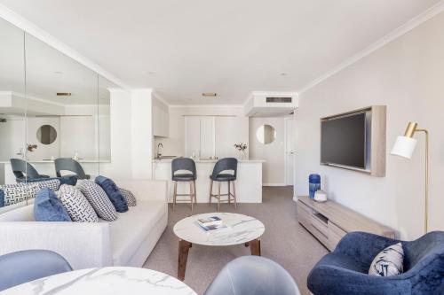 a living room with a couch and chairs and a tv at The Sebel Quay West Suites Sydney in Sydney