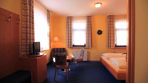 a hotel room with a bedroom with a bed and a desk at Hotel Stadt Suhl in Zella-Mehlis