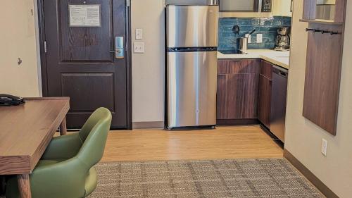 a kitchen with a stainless steel refrigerator and a table at Staybridge Suites Bismarck by IHG in Bismarck